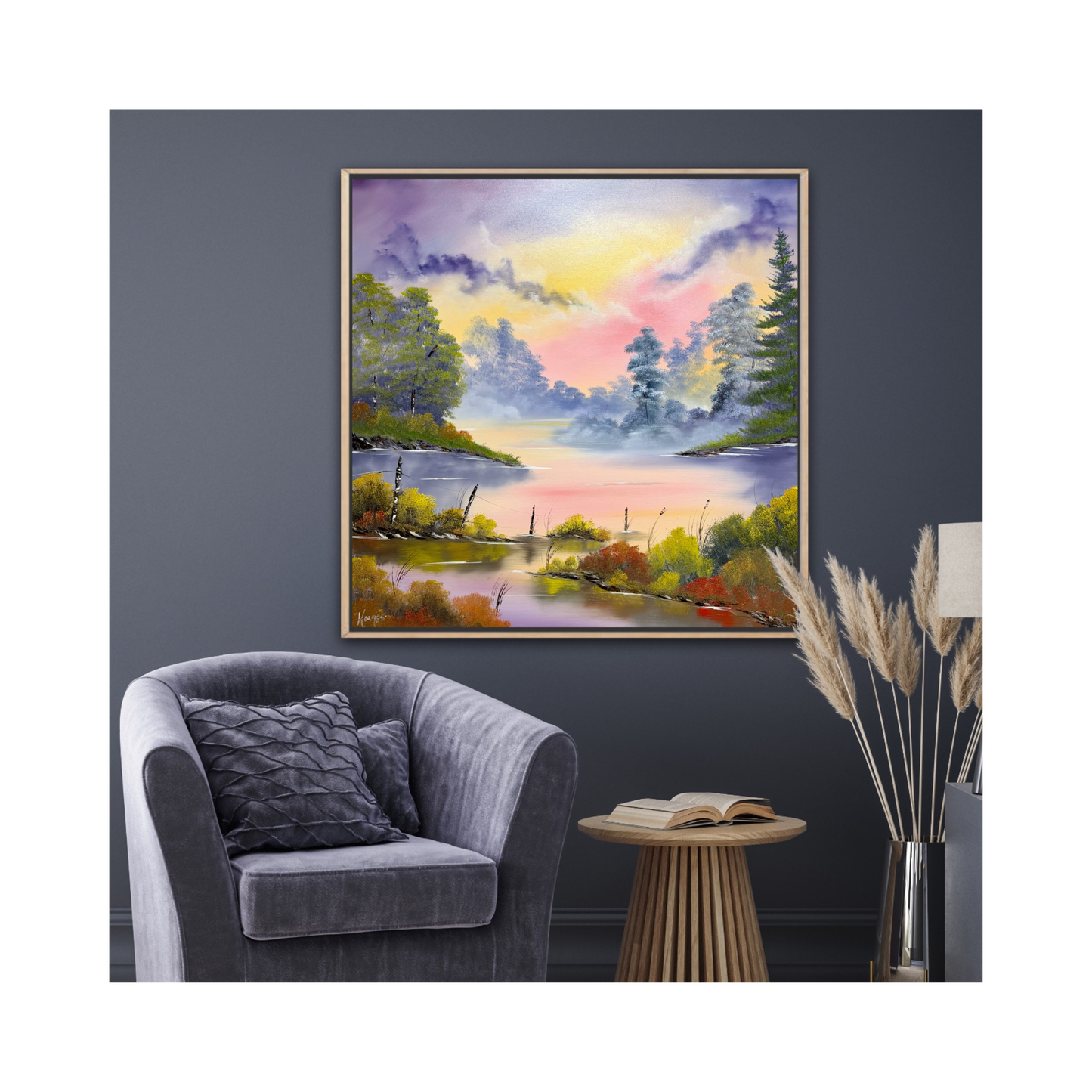 Framed landscape painting on a wall above a gray armchair with a side table and decorative elements.