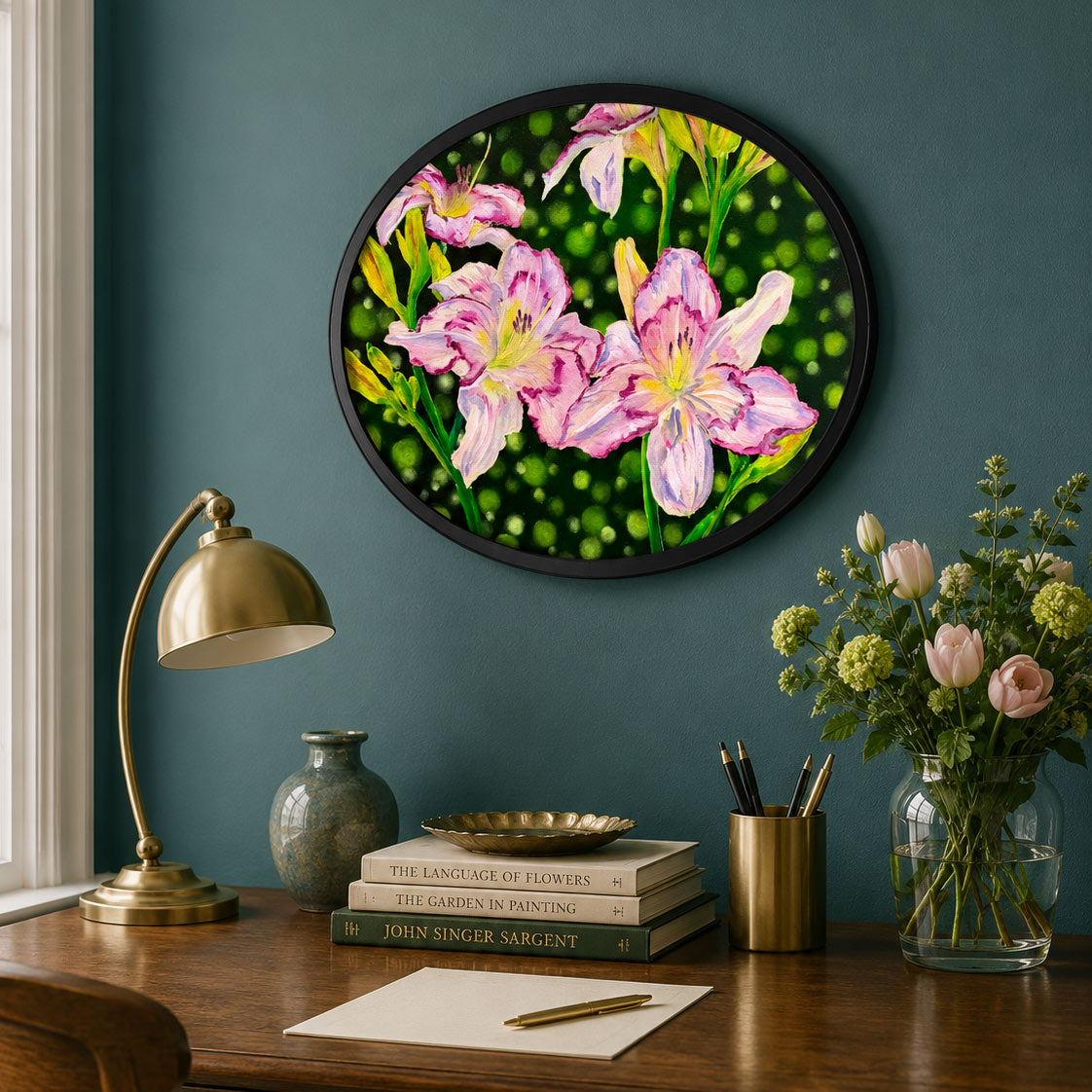 A round framed floral wall art piece hangs on a dark teal wall above a wooden desk. The artwork shows large pink flowers with yellow centers on a green dotted background.