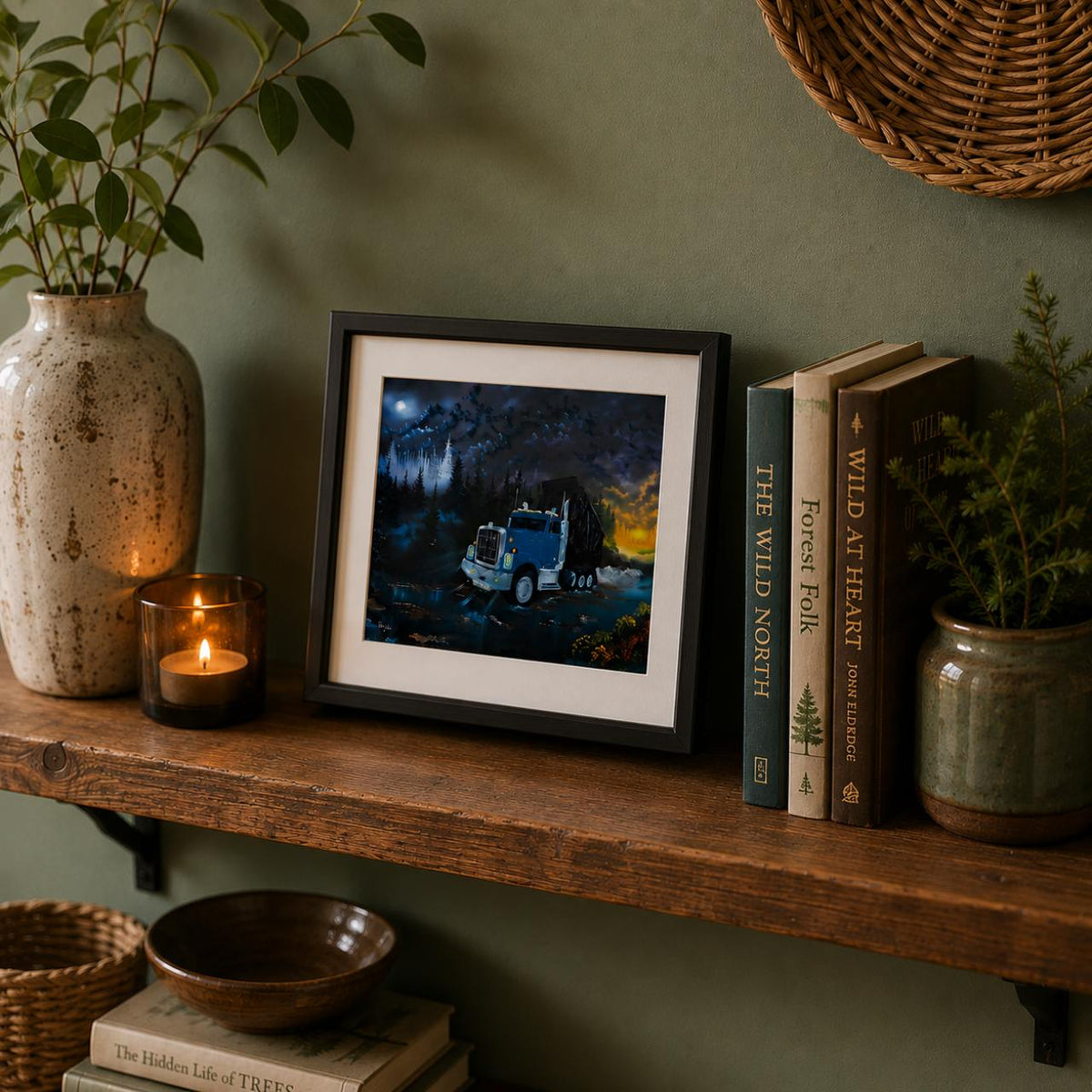 A framed art print depicting a blue semi-truck at night under a full moon, styled on a rustic wooden shelf with books, a candle, and potted plants against a sage green wall.