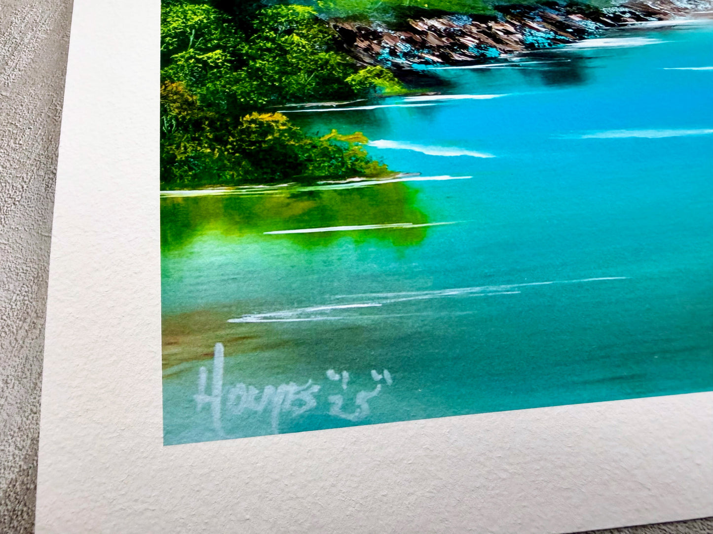 Close-up of a scenic landscape with water and greenery, signed at the bottom.