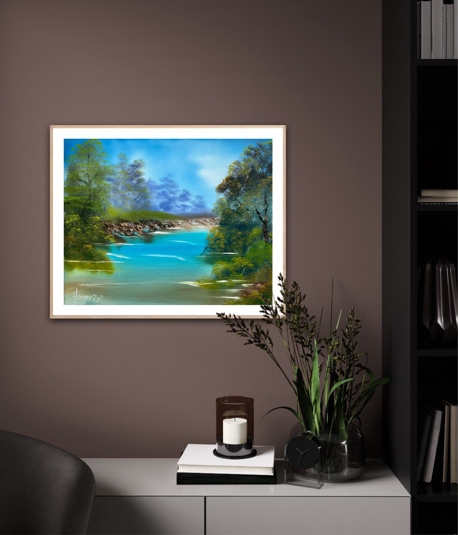 Framed painting of a landscape with a lake on a wall in a room.