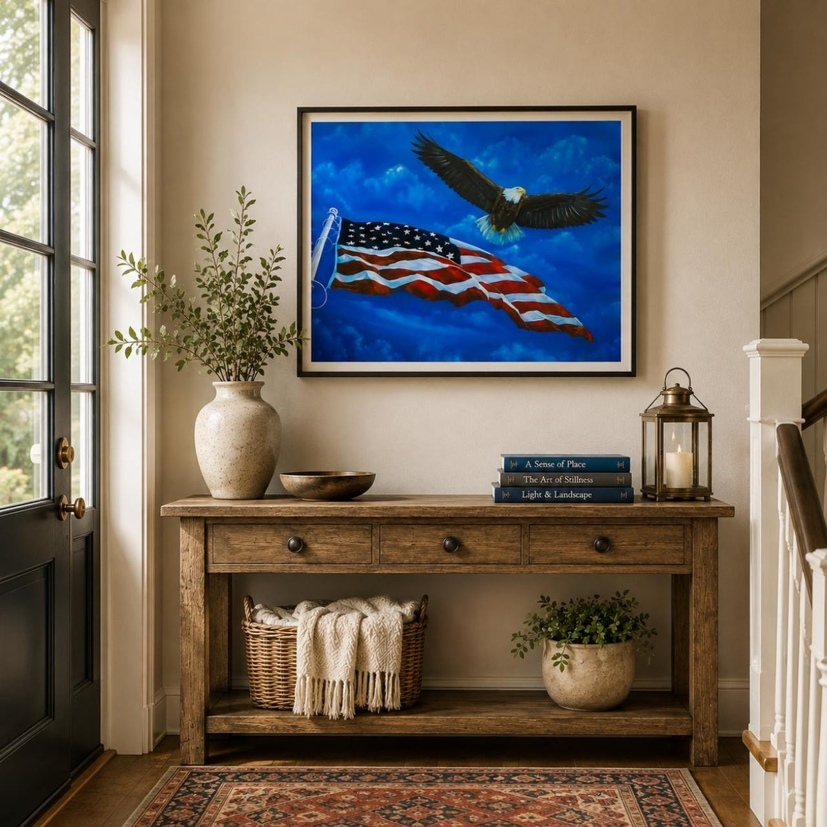 A framed art print depicting a bald eagle flying over a waving American flag, hung on a natural color wall above a rustic wooden console table in a styled entryway.
