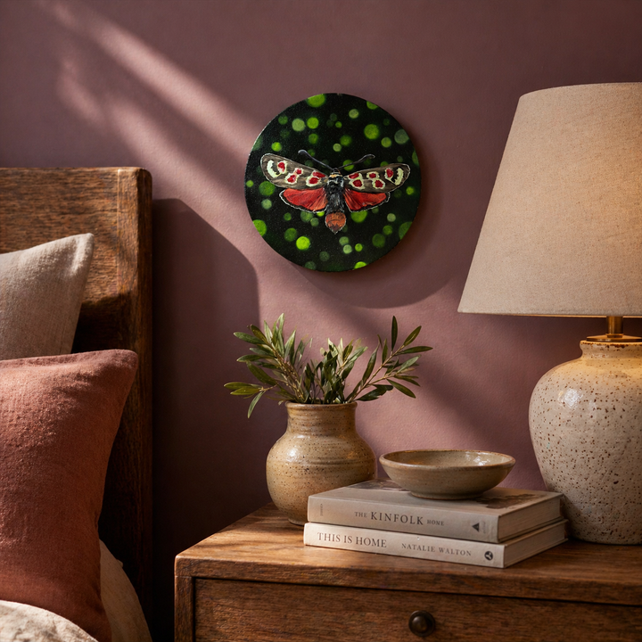 Lucy red white and brown moth 8" original oil painting on round canvas in the bedroom above night stand with books lamp and flower vase