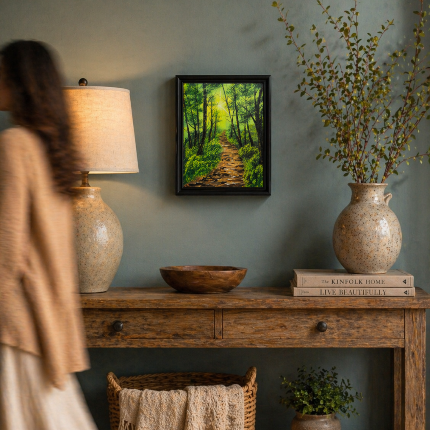 Original oil painting of a woodland path in a hallway with a wooden console table, lamp and green wall.