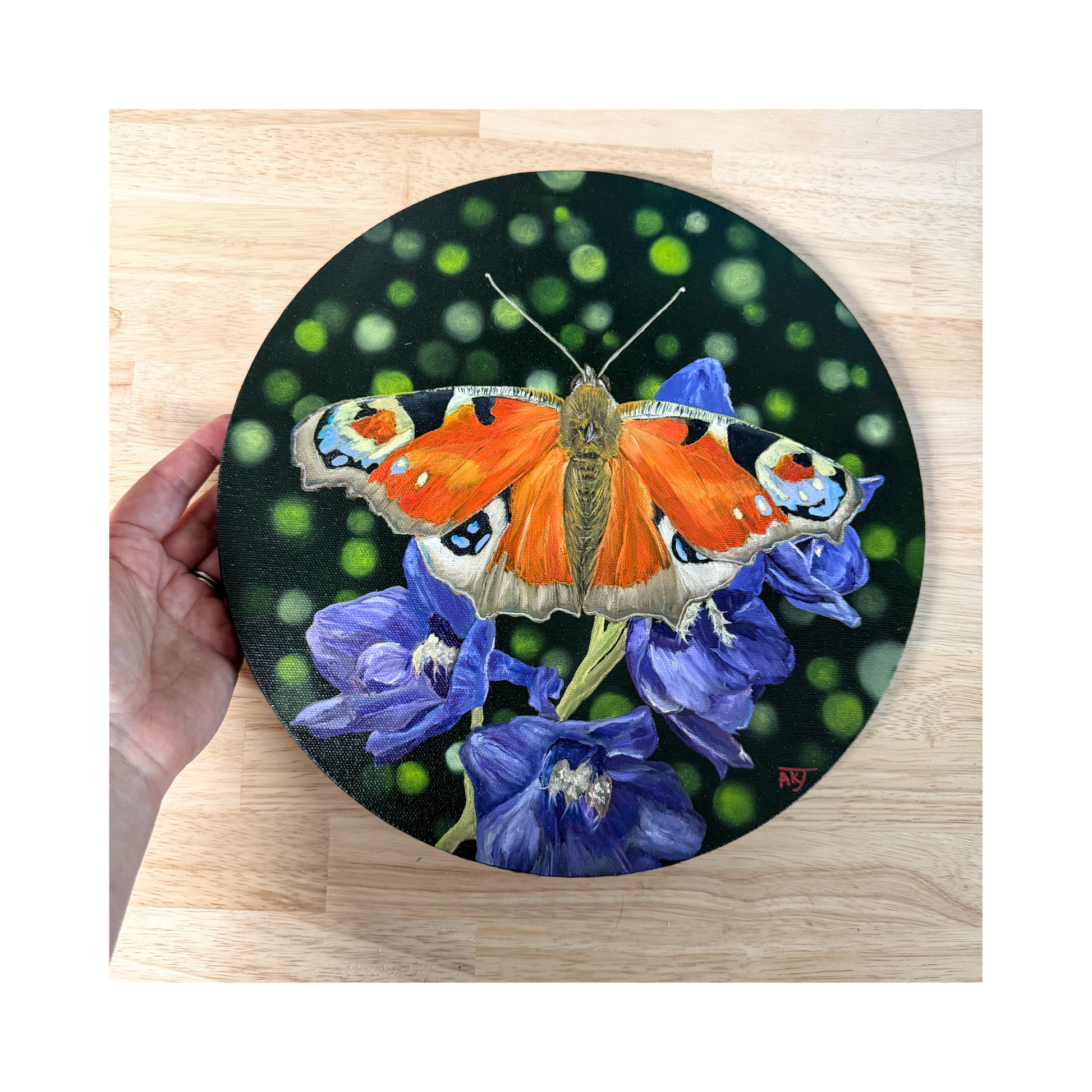 Original oil painting of a peacock butterfly sitting on purple delphinium flowers on a 12" round canvas top view