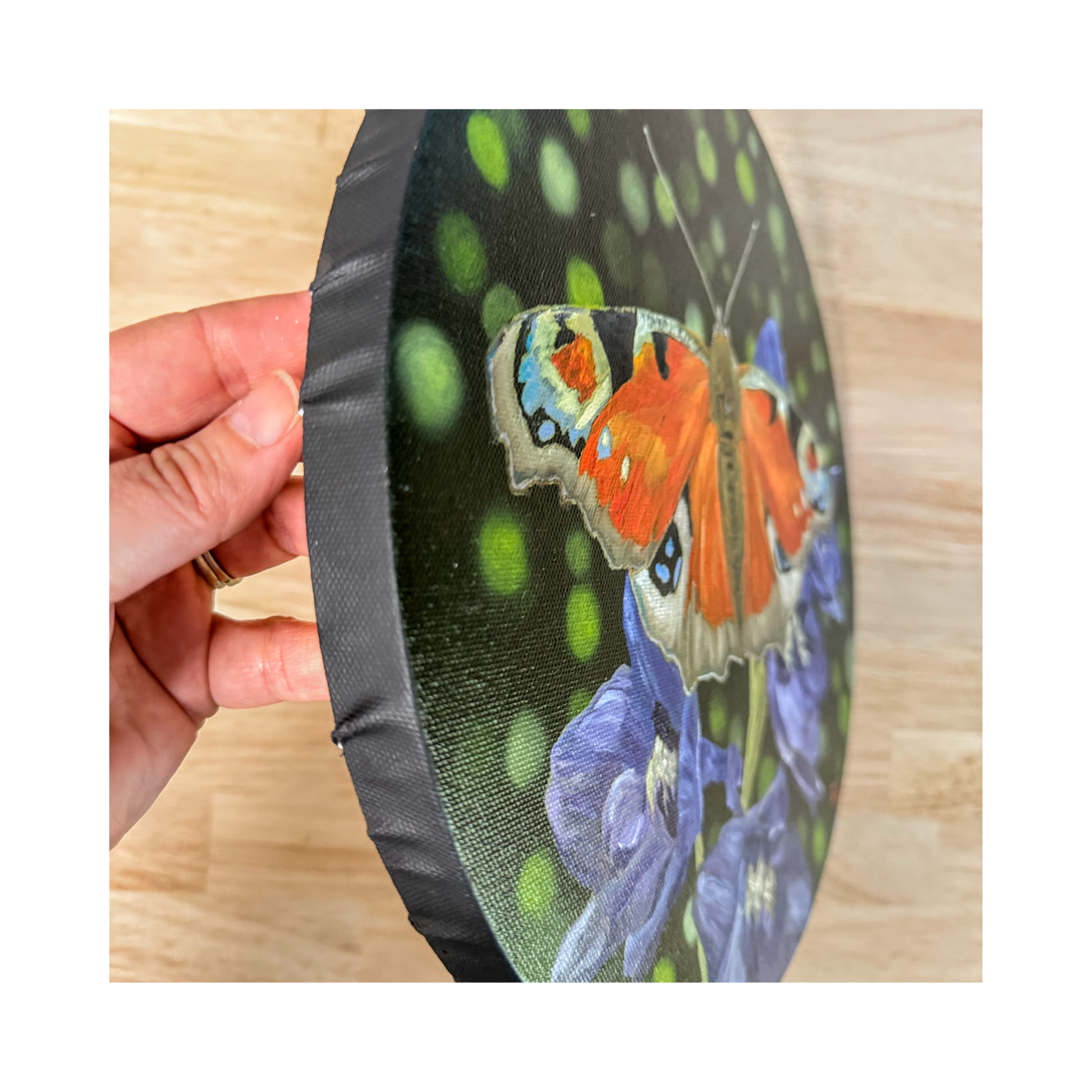Original oil painting of a peacock butterfly on 12" round canvas side view showing black edge