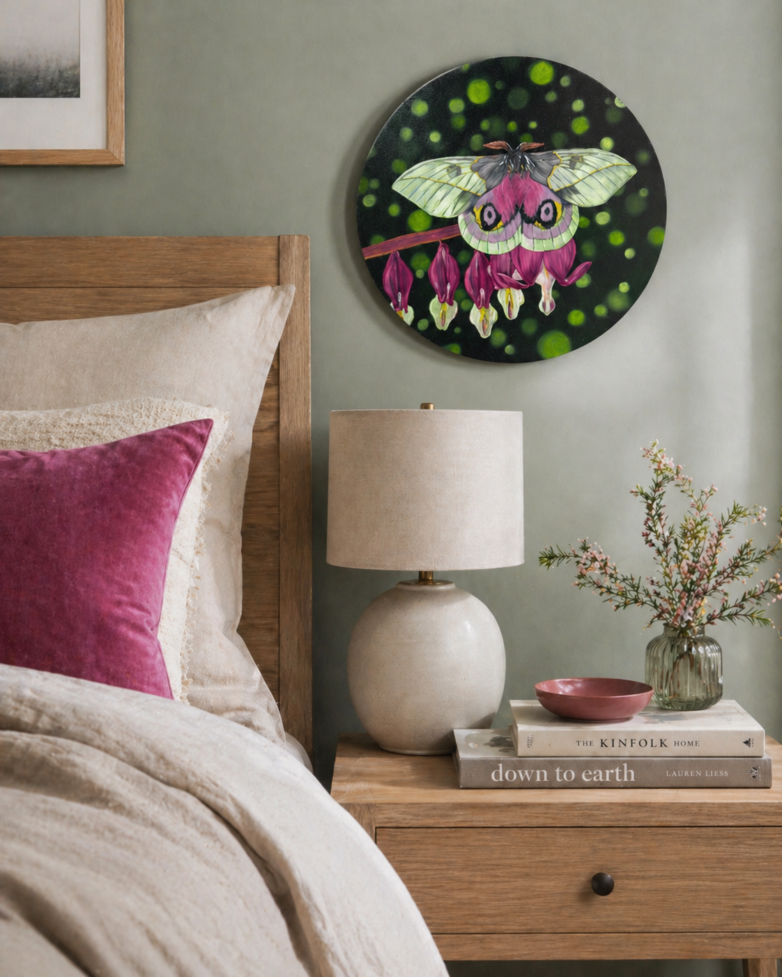 Original oil painting of a white and pink moth on a 12" round canvas - displayed in a bedroom over the night stand with books and a lamp