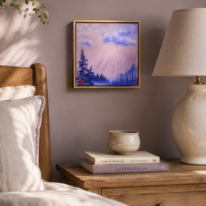 Bedroom with wooden bed, framed purple and pink landscape artwork, lamp, and books on a nightstand.