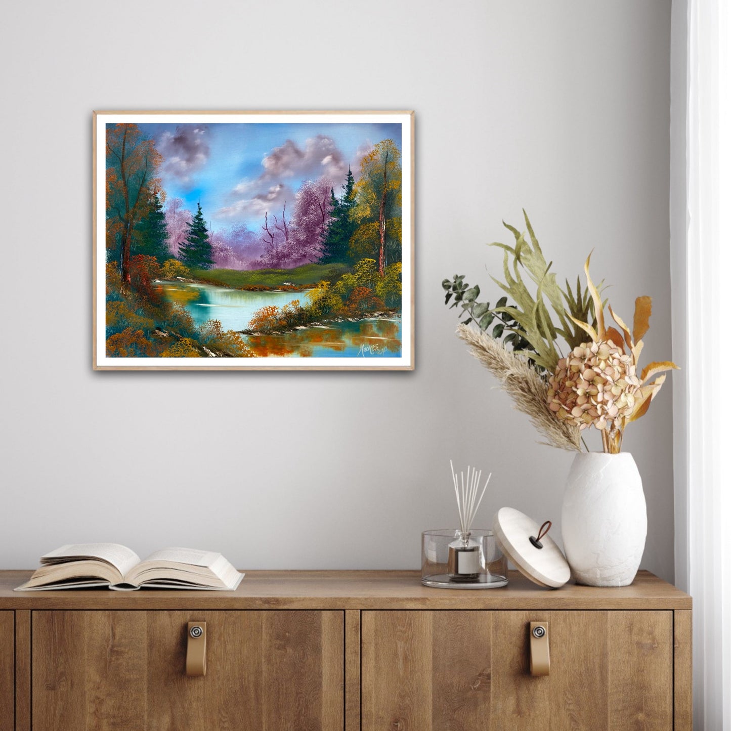 Framed landscape painting on a wall above a wooden cabinet with decorative items.