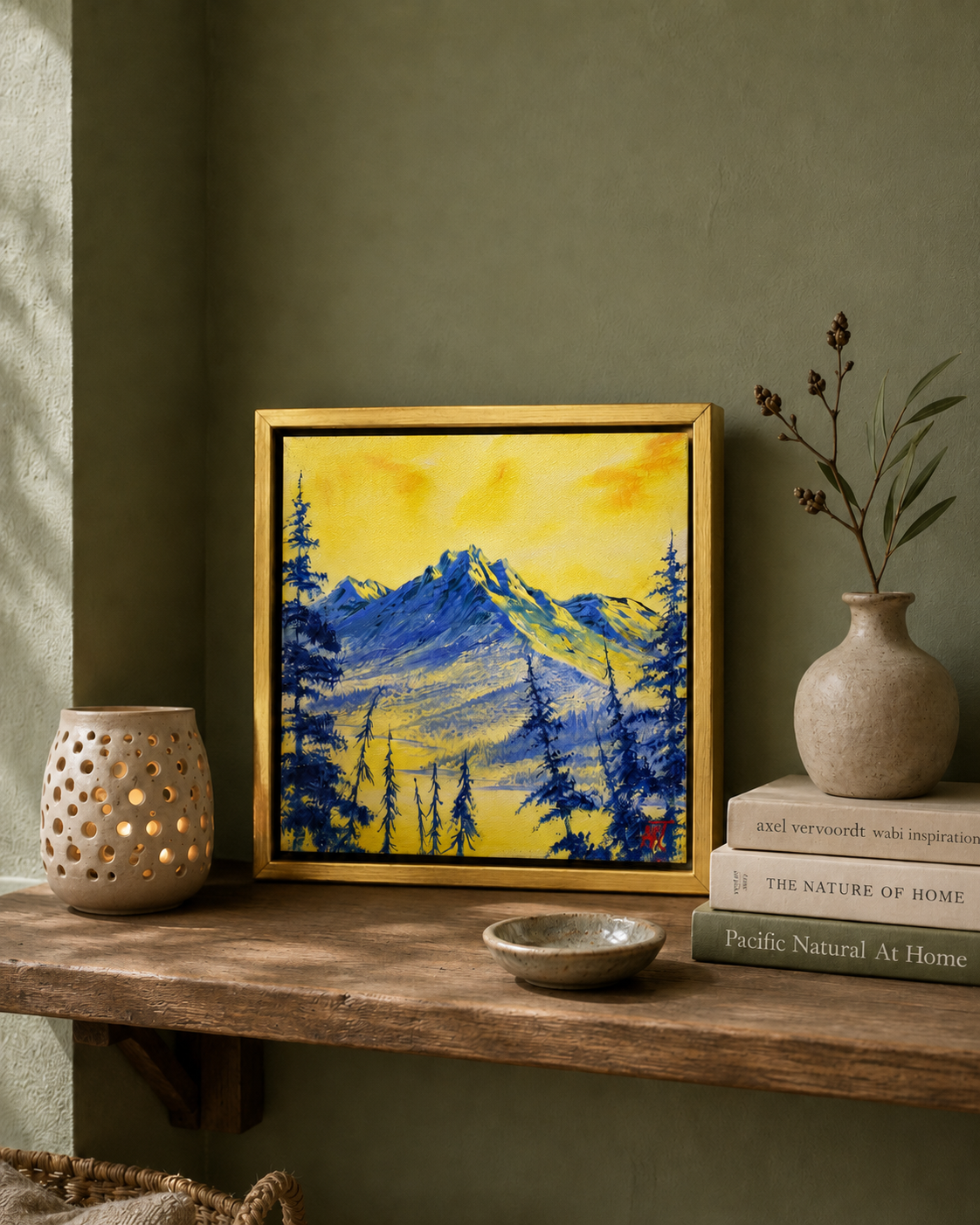 Framed mountain landscape painting on a wooden shelf with decorative items.
