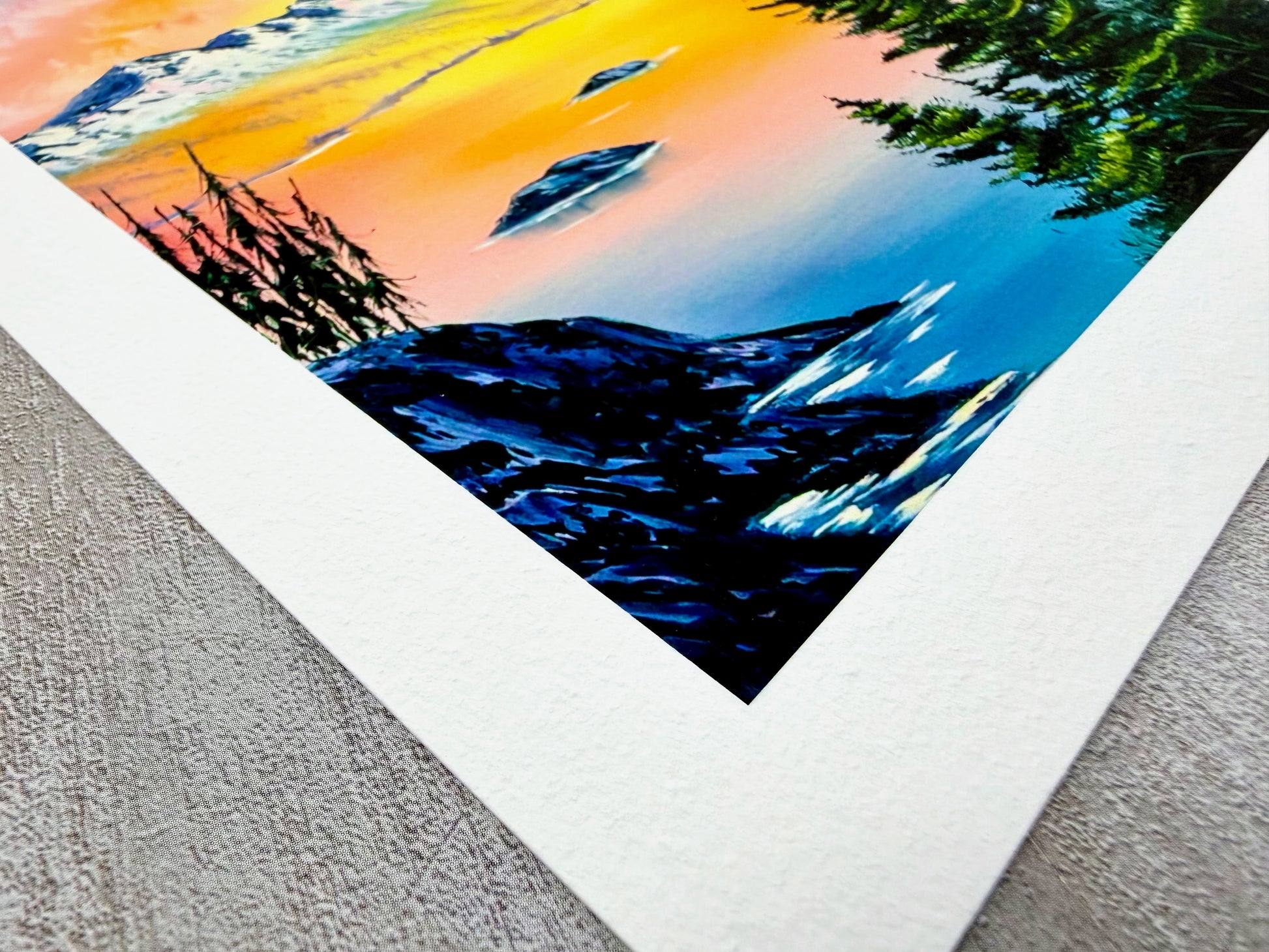 Colorful mountain landscape print with a white border on a textured surface