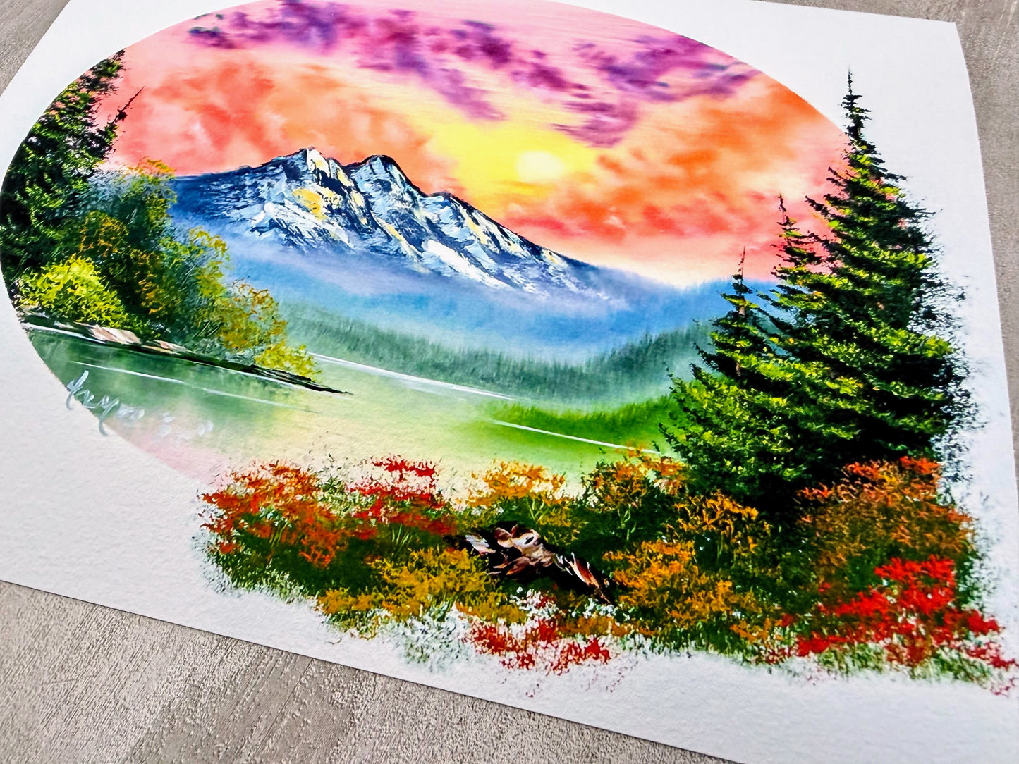 Colorful landscape painting of a mountain, trees, and flowers on a white background.